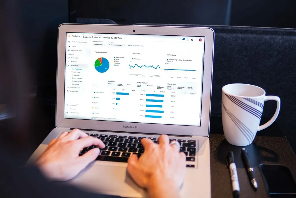 Person typing on a laptop displaying analytics graphs and data metrics in canada